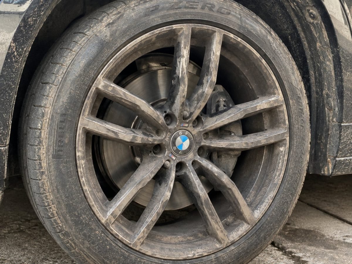 The same BMW alloy wheel before detailing, coated in brake dust and road grime
